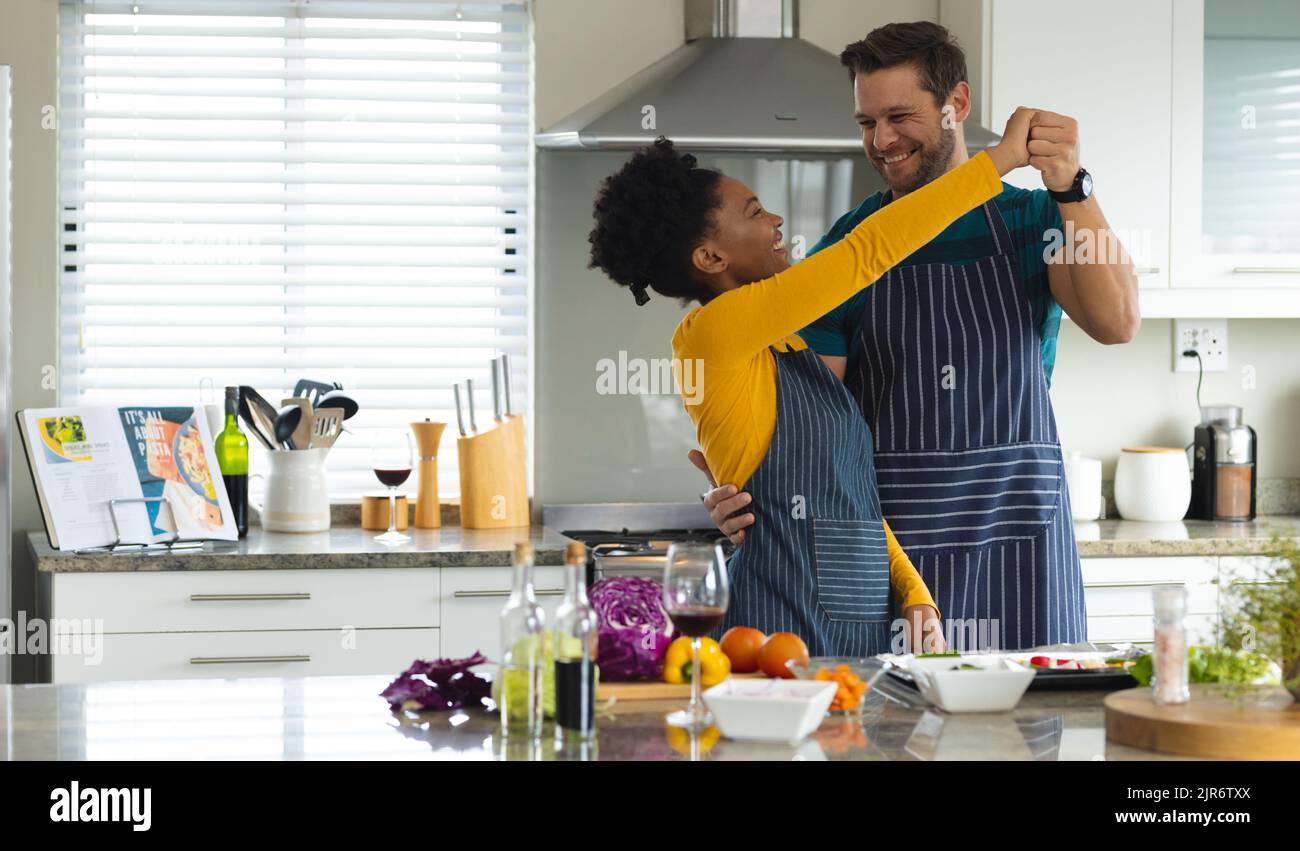 Image of happy diverse couple dancing in kitchen Stock Photo