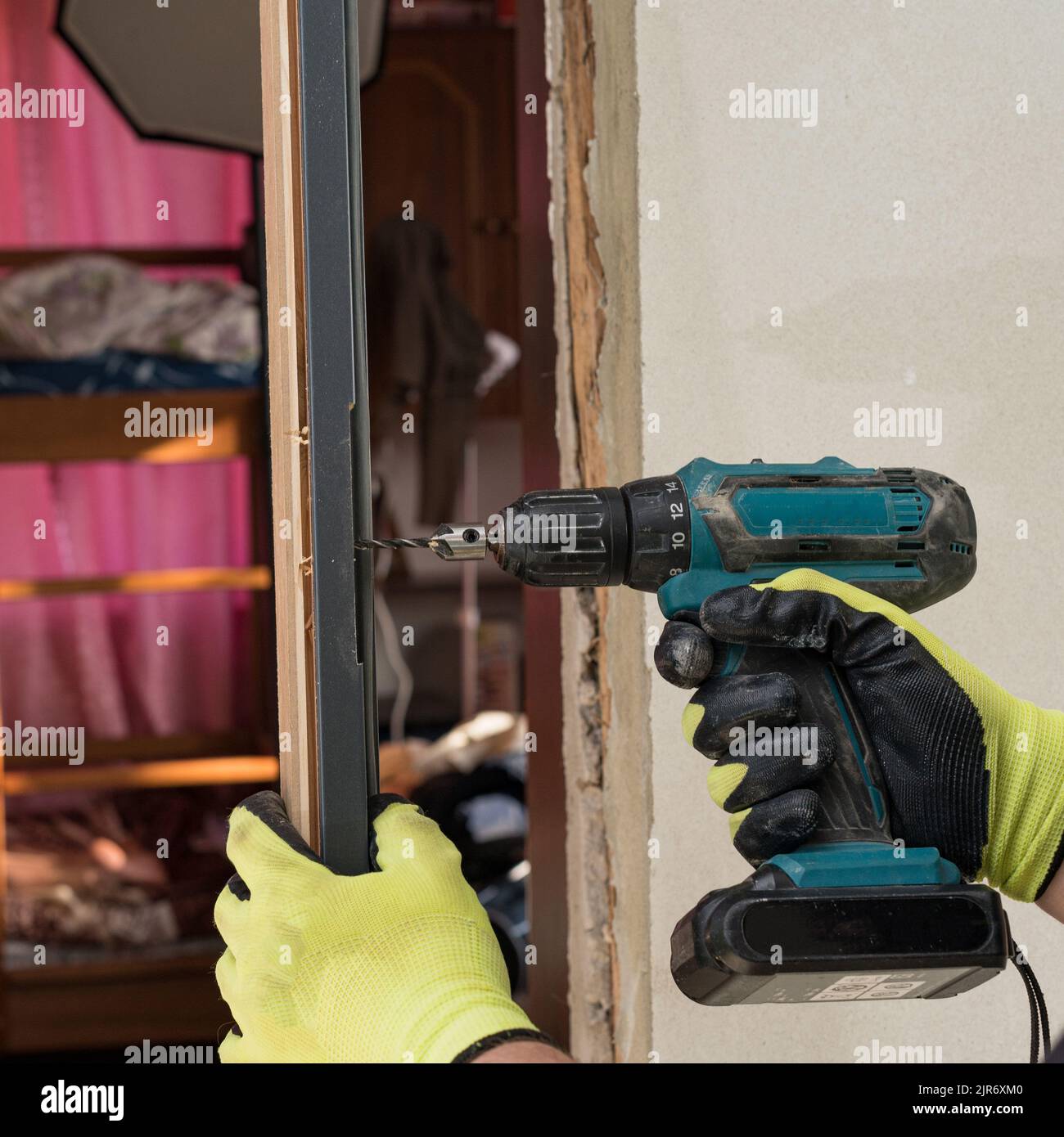 The craftsman drills a hole in the door frame for subsequent attachment