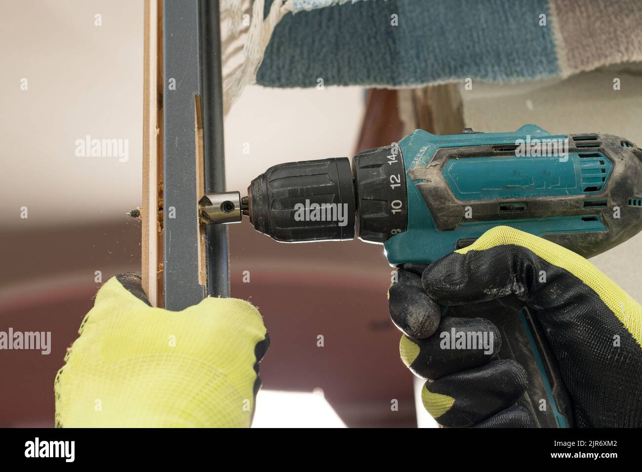 Drilling a hole in the door with a green screwdriver, closeup of the