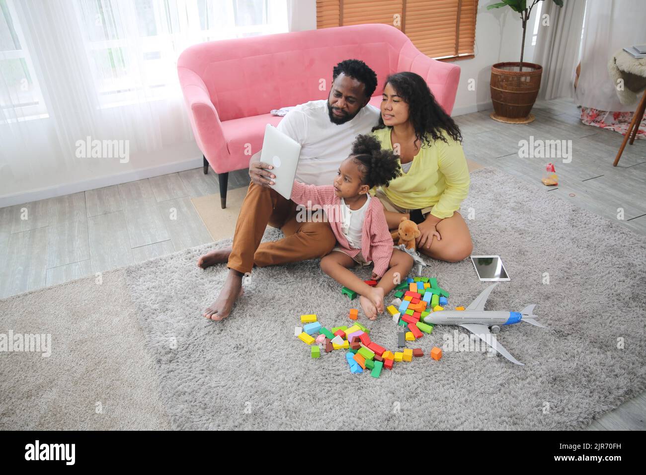 Shot of happy interracial family of mother father and their daughter inside modern apartment. Stock Photo