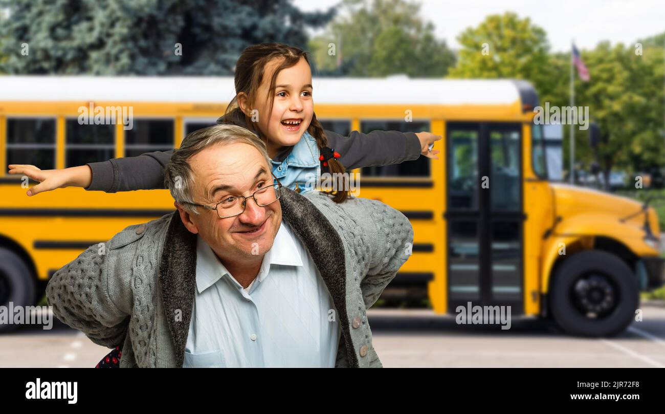 a little girl with her grandfather near the school bus Stock Photo