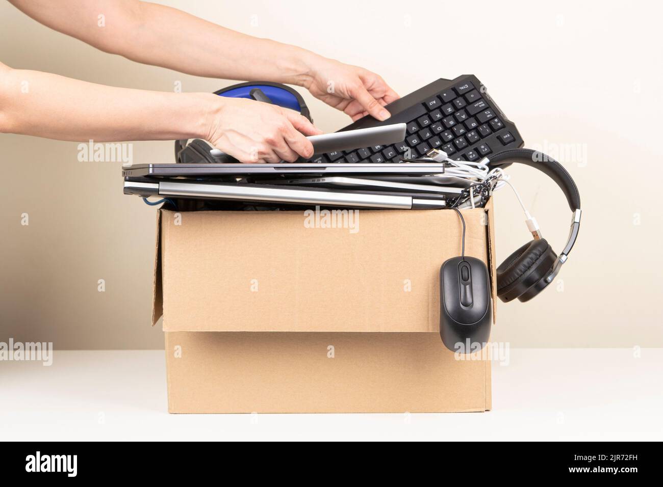 Female hands put tablet computer and keyboard in box full old used