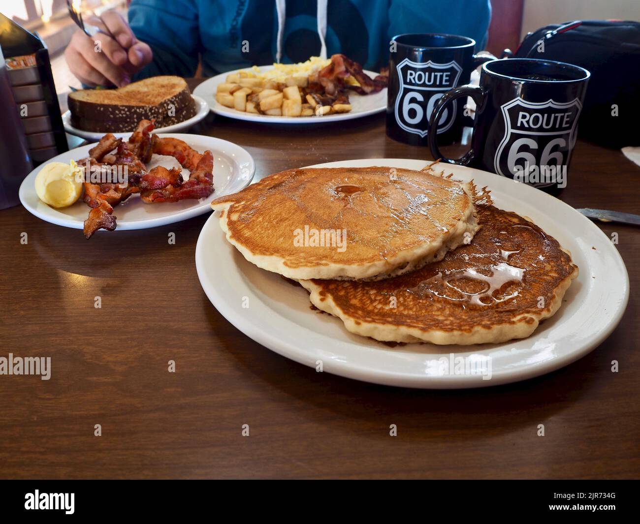 An American breakfast with coffee cups, pancakes, butter and toast in a coffee bar Stock Photo