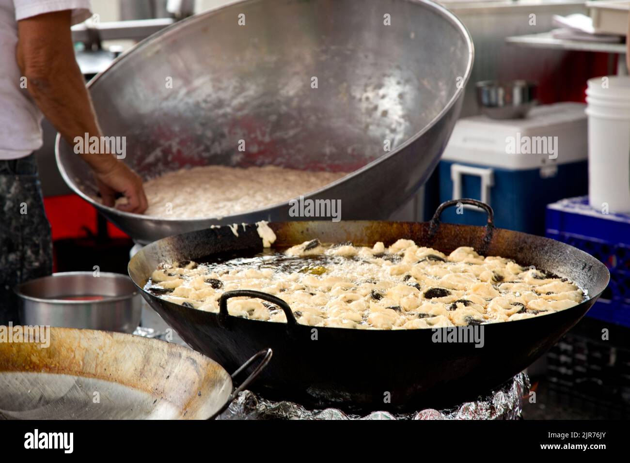 Bin of fresh hot deep fried zeppole donuts being prepared in a deep fryer. Stock Photo