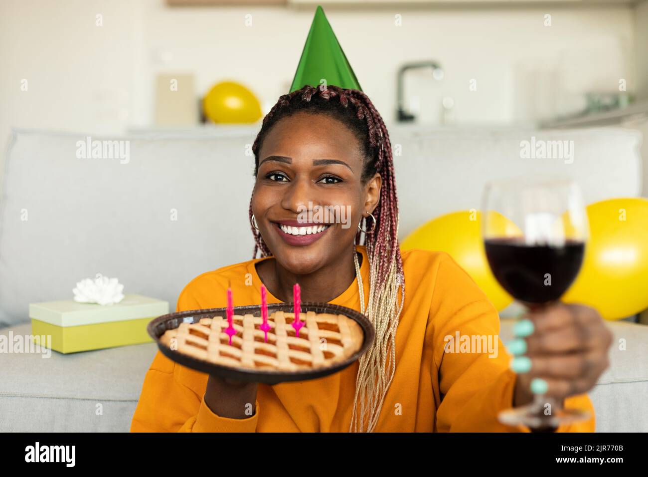 Birthday concept. Excited black lady holding glass of wine and pie with