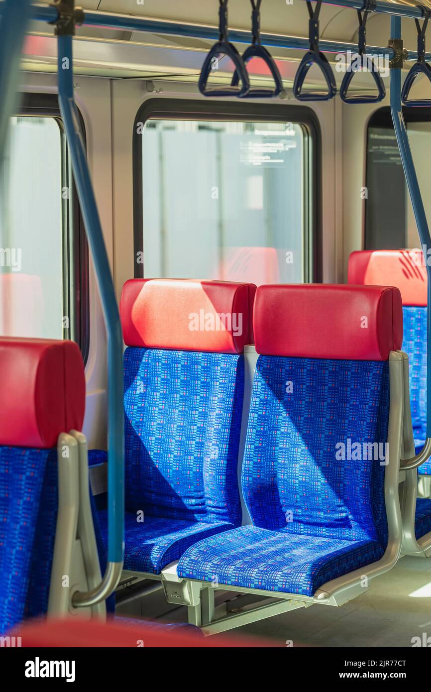 Pair of empty blue red seats in public transport car illuminated by sun