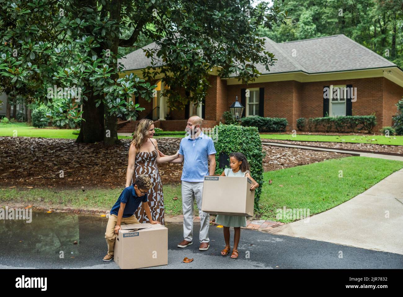 A blended family mom and dad and two young children holding packing ...