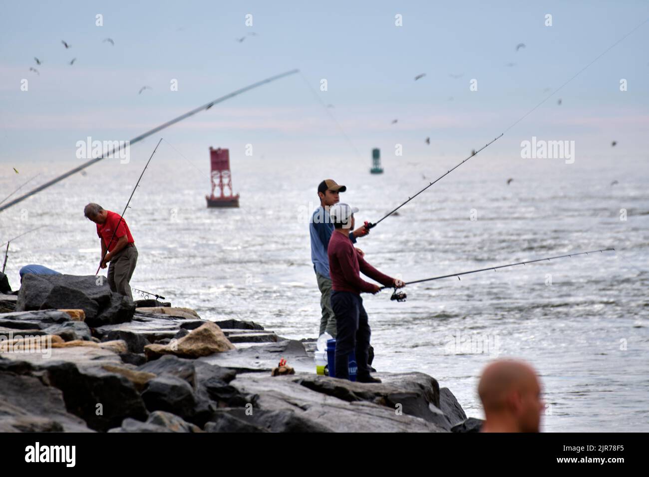 Summer anglers fish from the rocks along Indian River Inlet in Sussex County, Delaware USA. Stock Photo