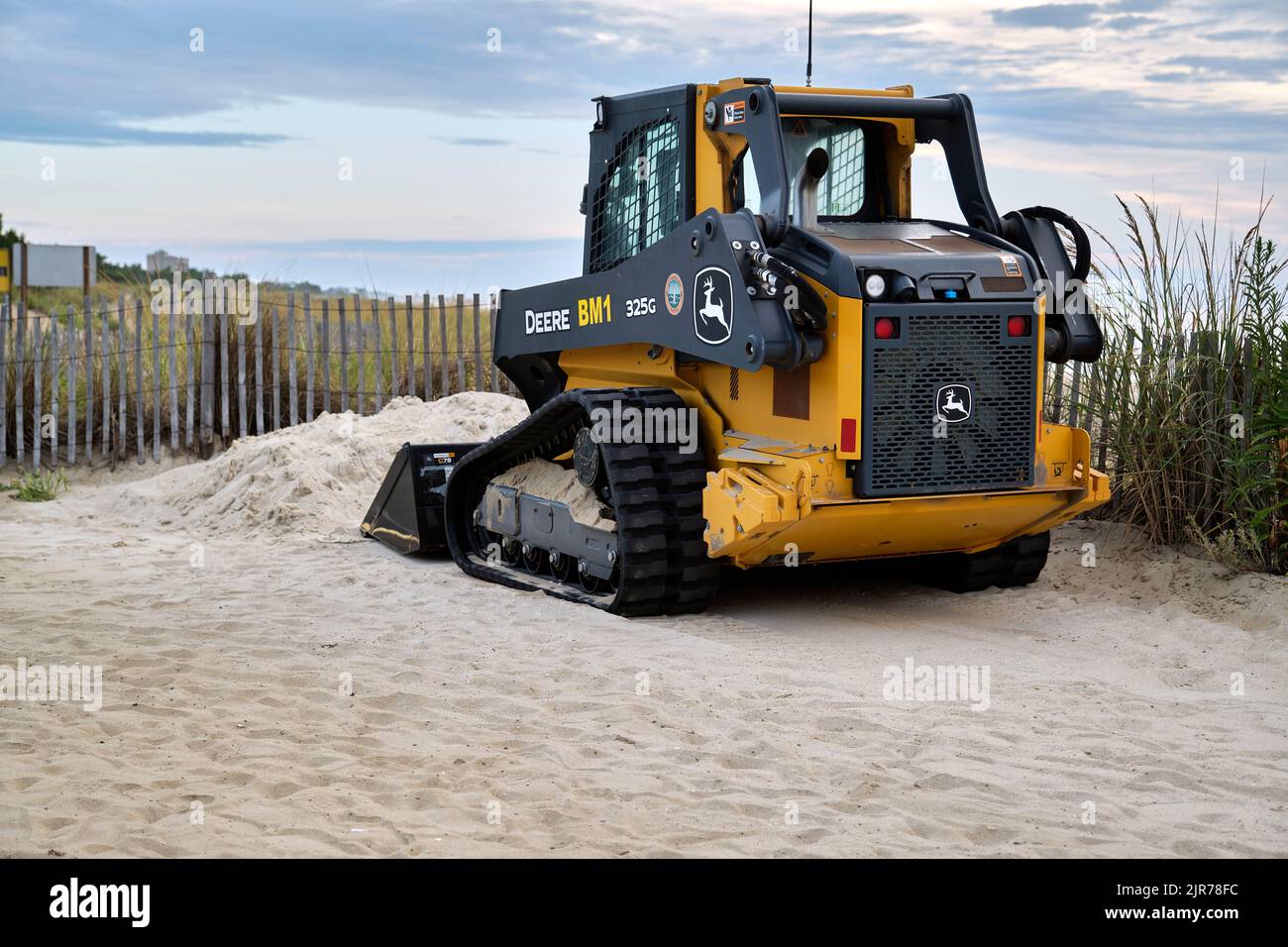 A Deere 325G track loader moves beach sand in an effort to repair tidal erosion. Stock Photo