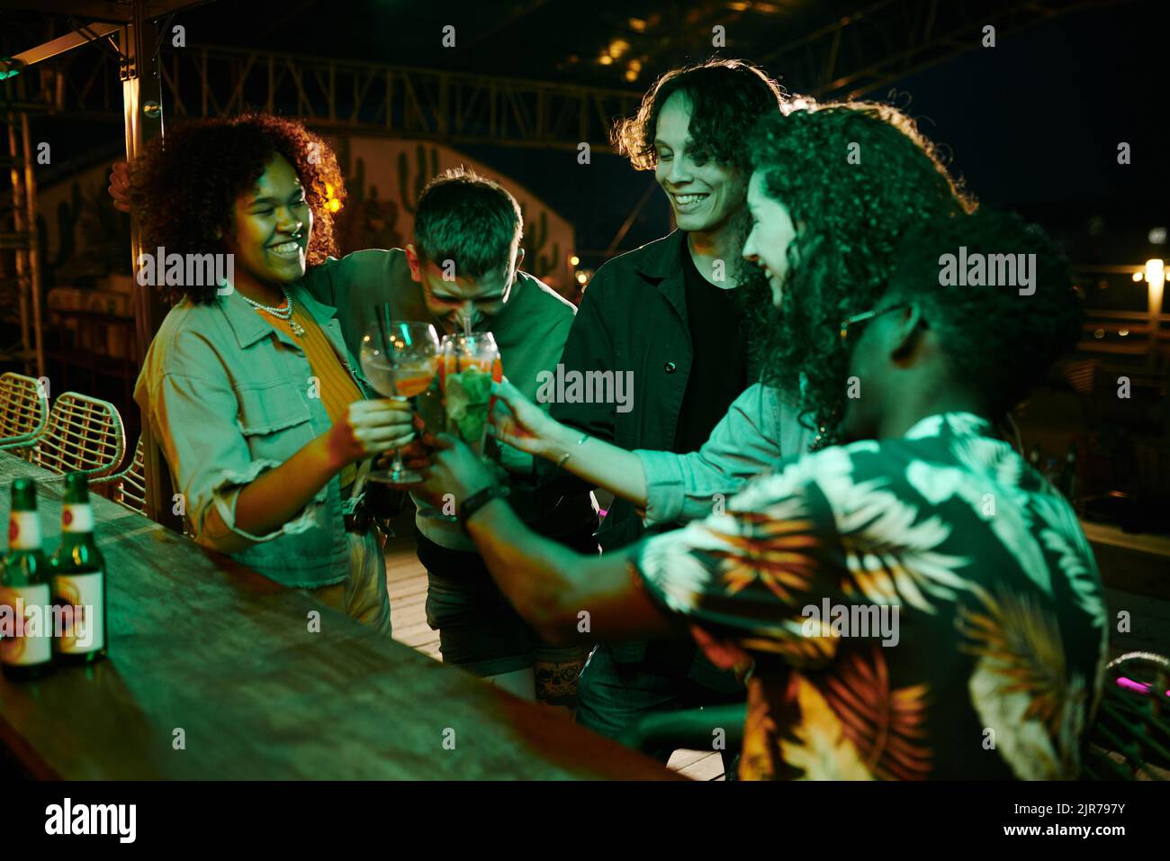 Group of joyful intercultural friends clinking with glasses of