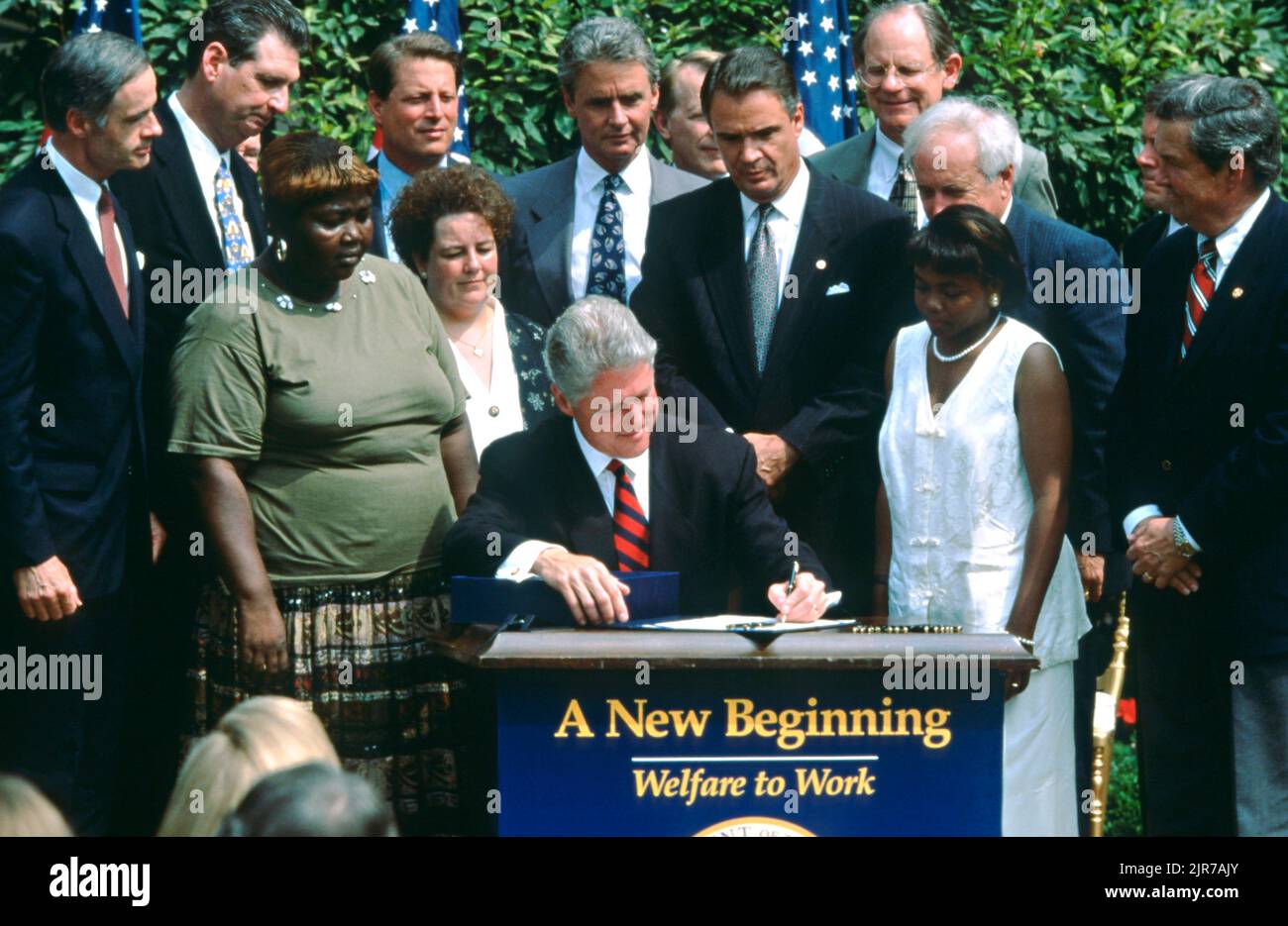 U.S. President Bill Clinton, surrounded by members of Congress and guests, signs the Welfare Reform Act during a ceremony in the Rose Garden of the White House August 22, 1996 in Washington, DC. Former welfare recipients Lillie Harden of Arkansas, left,  Janet Ferrel, of West Virginia and Penelope Howard of Delaware stand next to the president. Stock Photo