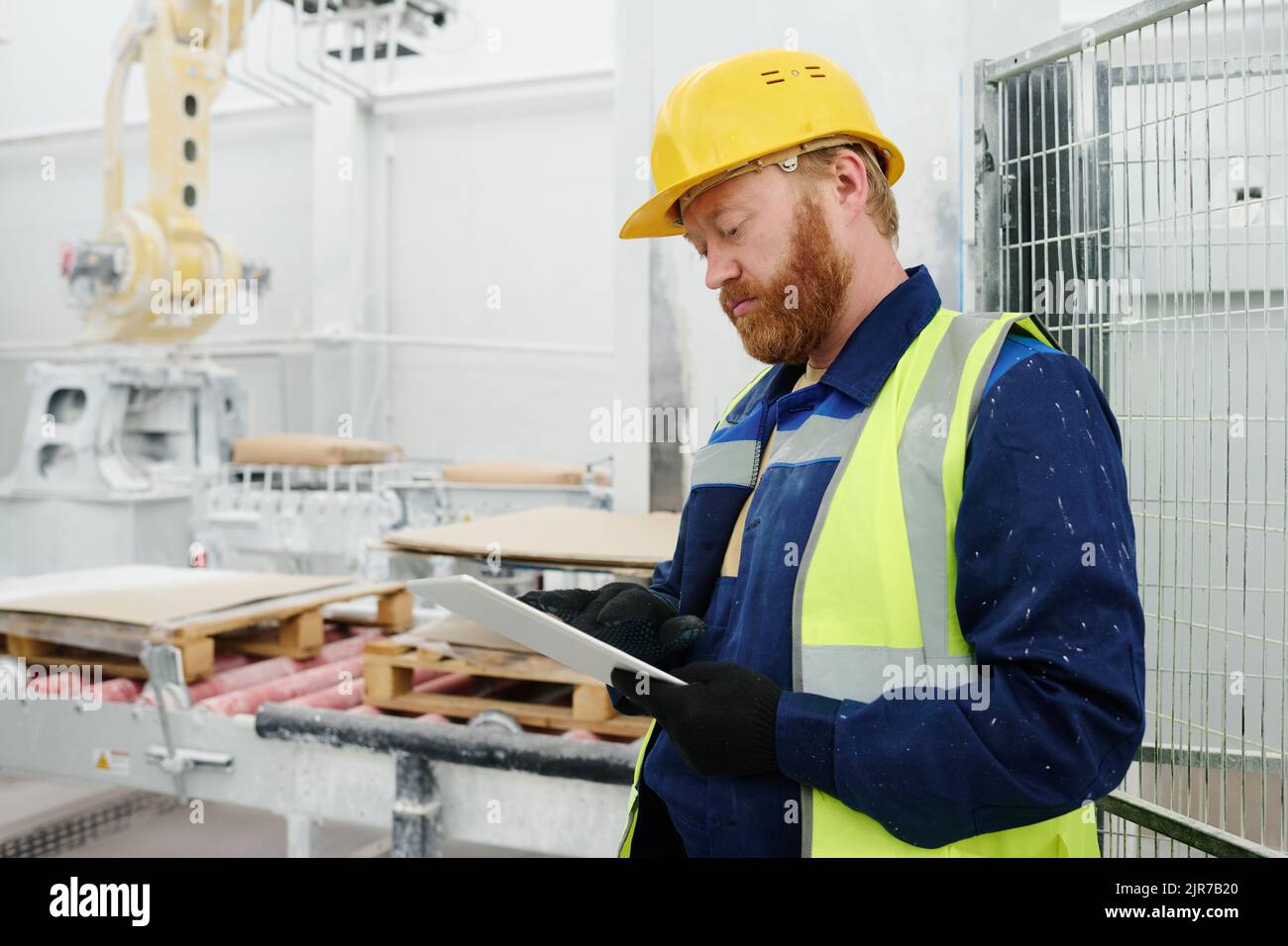 Young serious technician or foreman with tablet scrolling through