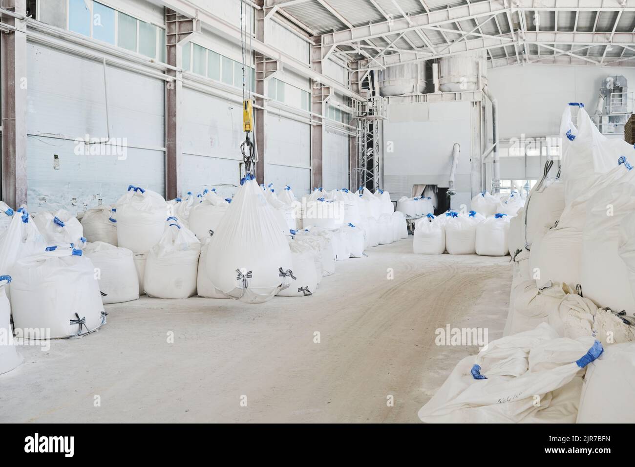 Spacious industrial plant or workshop of modern manufactory with heaps of huge and heavy white sacks with raw materials Stock Photo