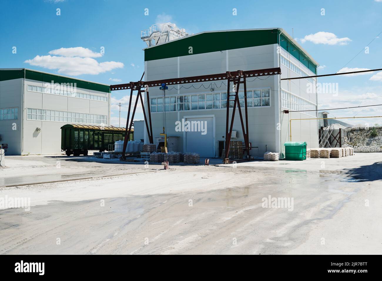 Two small white buildings of modern production factory standing in wide yard with blue sky and clouds above on sunny summer day Stock Photo