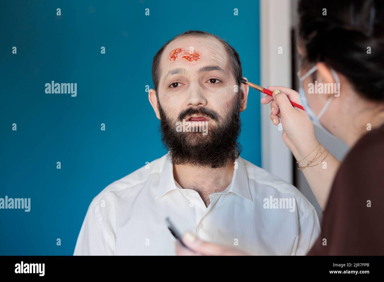Makeup artist using special effects to create zombie costume and scary