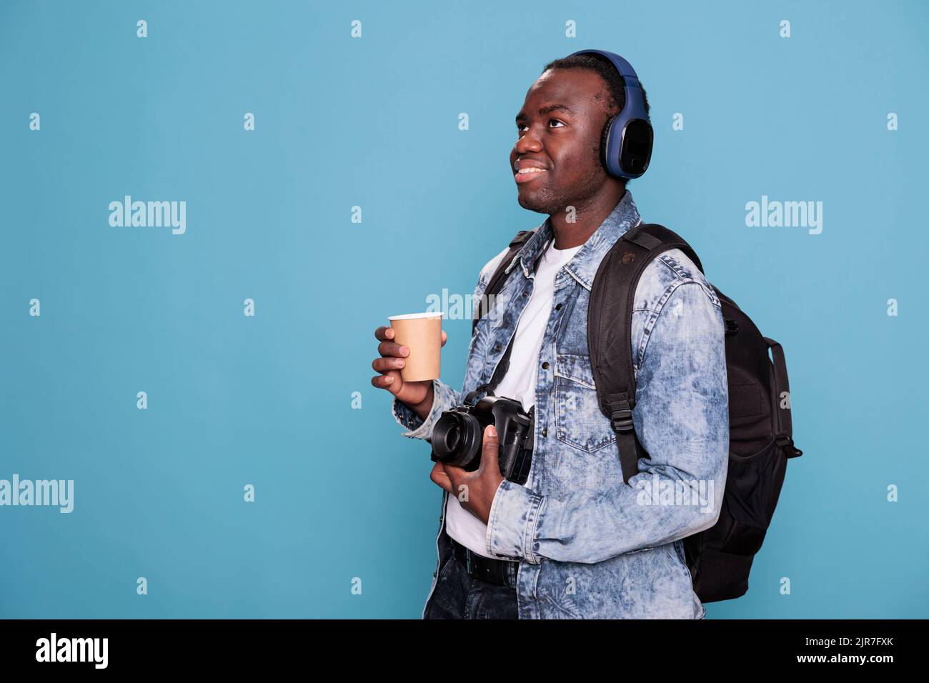 Smiling young man with professional camera and backpack going on