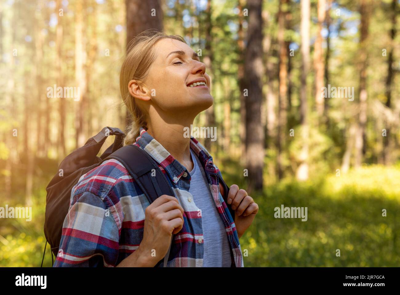 woman backpacker enjoy the nature in forest with eyes closed. outdoor relaxing. stress relief, mental health Stock Photo