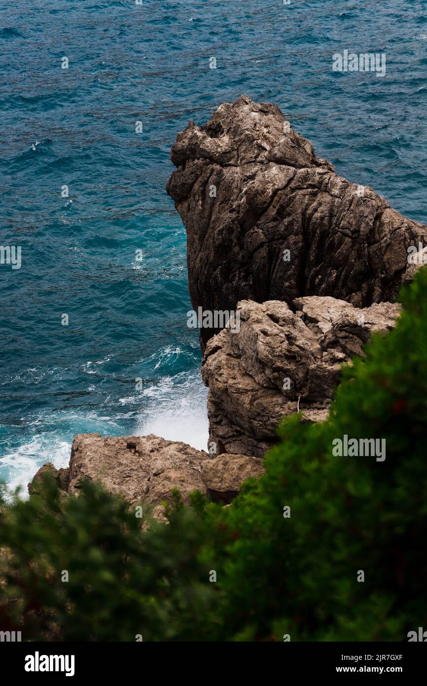 A vertical shot of the big rocks at the beach in the background of ...