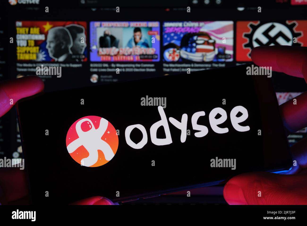 ODYSEE video platform logo seen on screen of smartphone and actual website seen on blurred laptop screen. New media platfom. Stafford, United Kingdom, Stock Photo