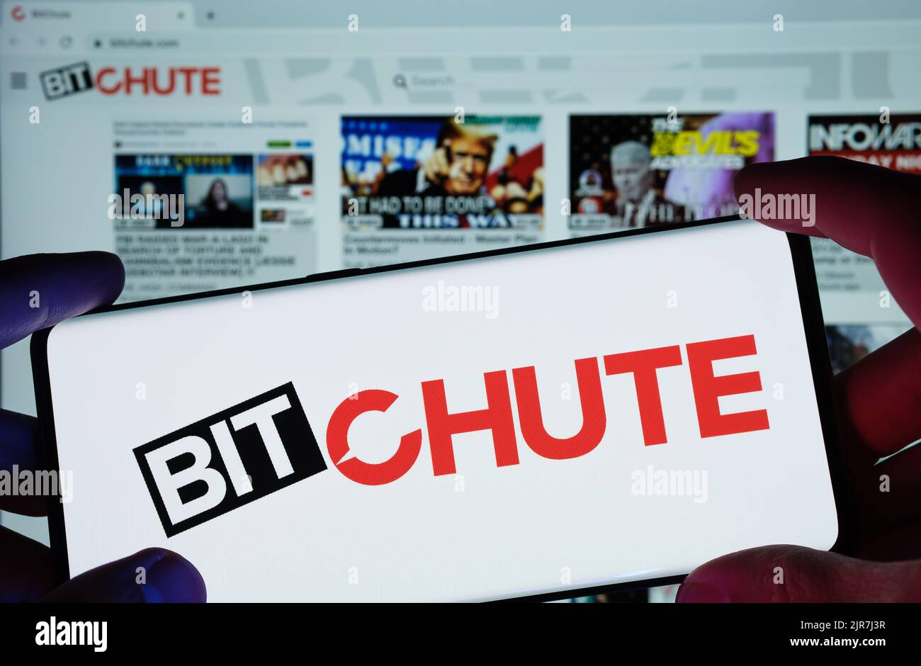 BitChute video platform logo seen on screen of smartphone and actual website seen on blurred laptop screen. New media platfom. Stafford, United Kingdo Stock Photo
