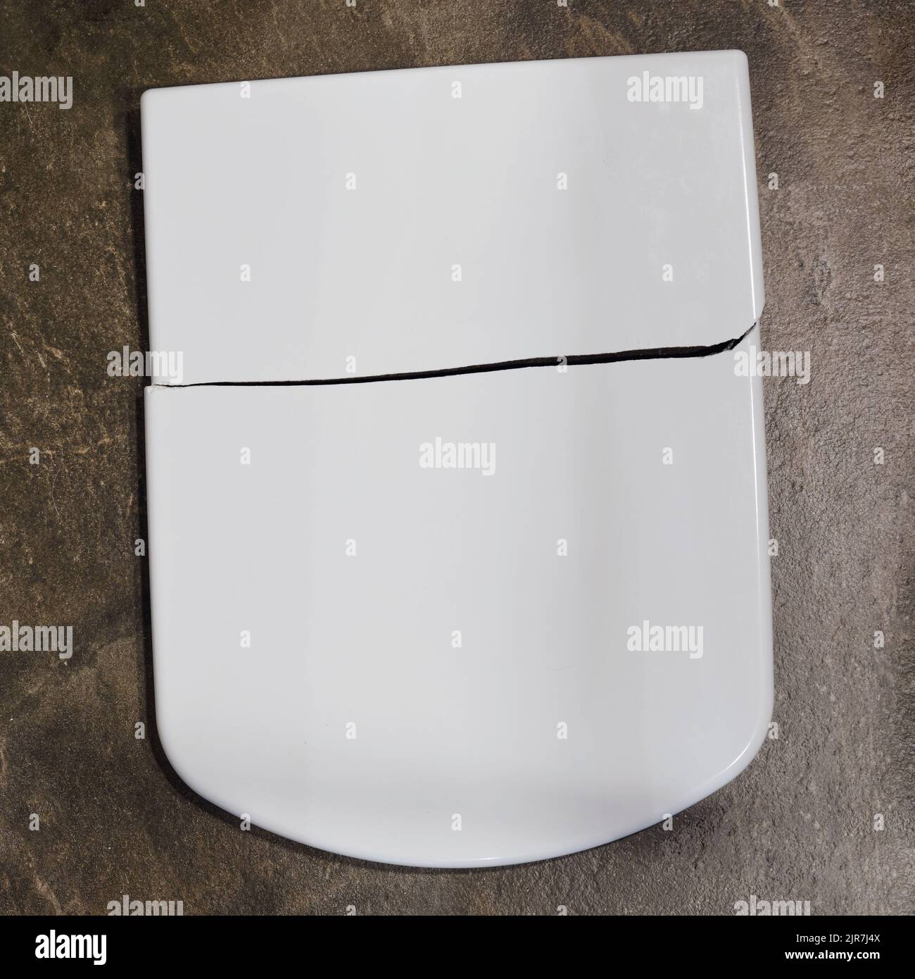 Cracked white toilet lid. A broken closing lid in the home toilet Stock