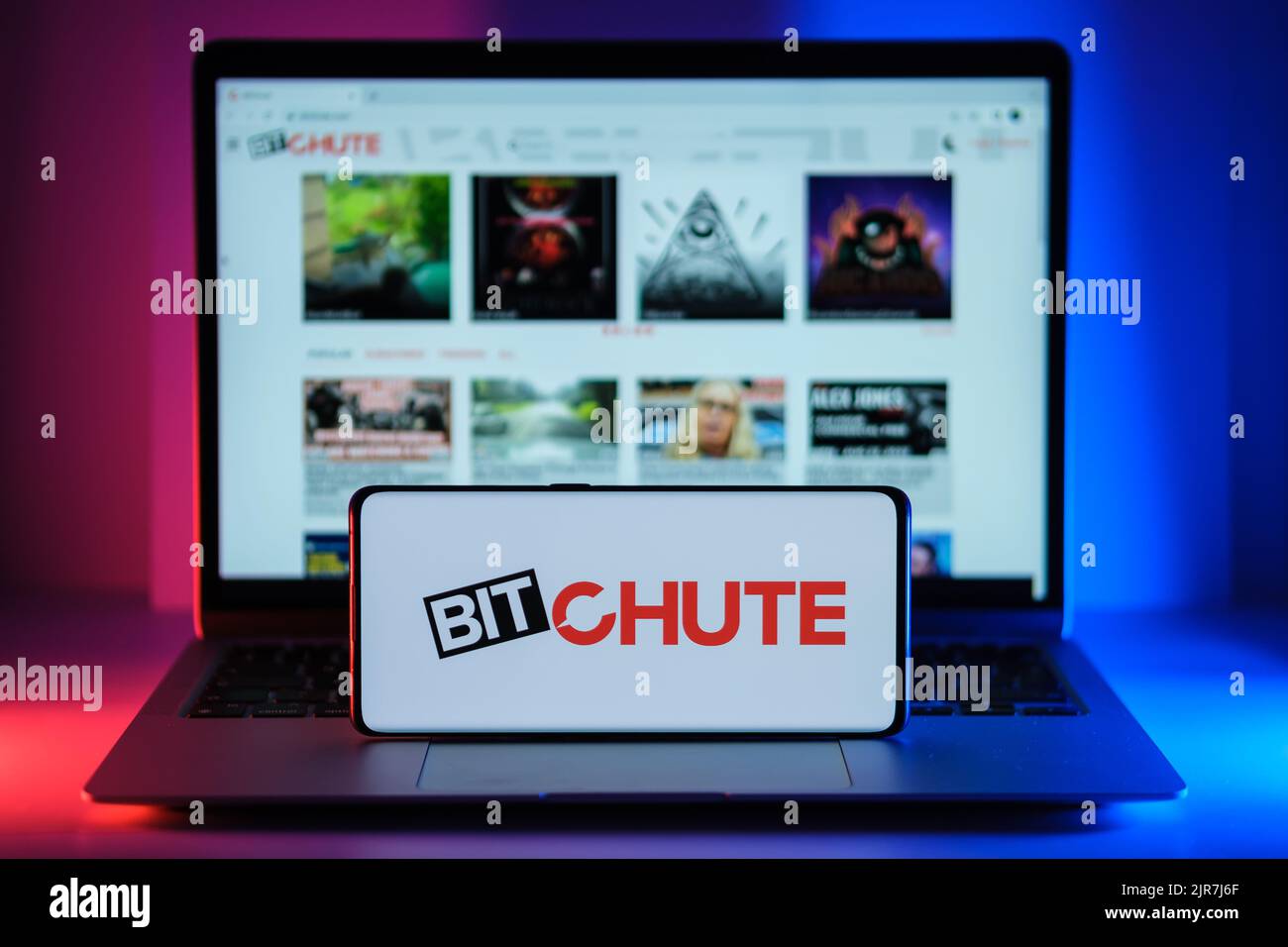 BitChute video platform logo seen on screen of smartphone and actual website seen on blurred laptop screen. New media platfom. Stafford, United Kingdo Stock Photo