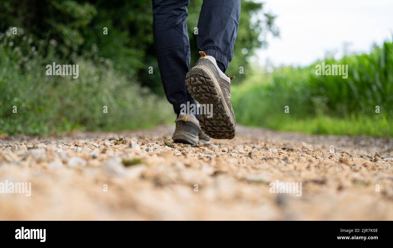 Low angle view of male legs with hiking shoes walking on a gravel ...