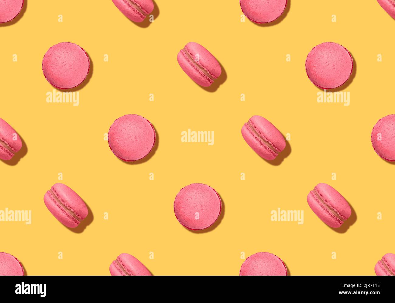 Pattern with almond cookies. Pink colored macaroons on bright yellow backdrop Stock Photo