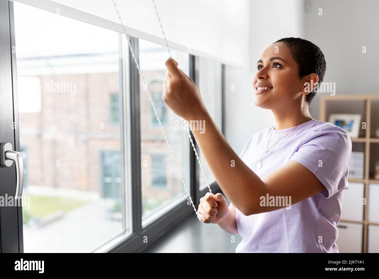 woman opening window roller blinds Stock Photo