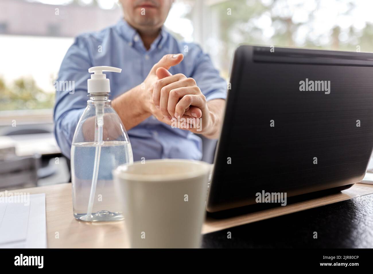 man using hand sanitizer at home office Stock Photo