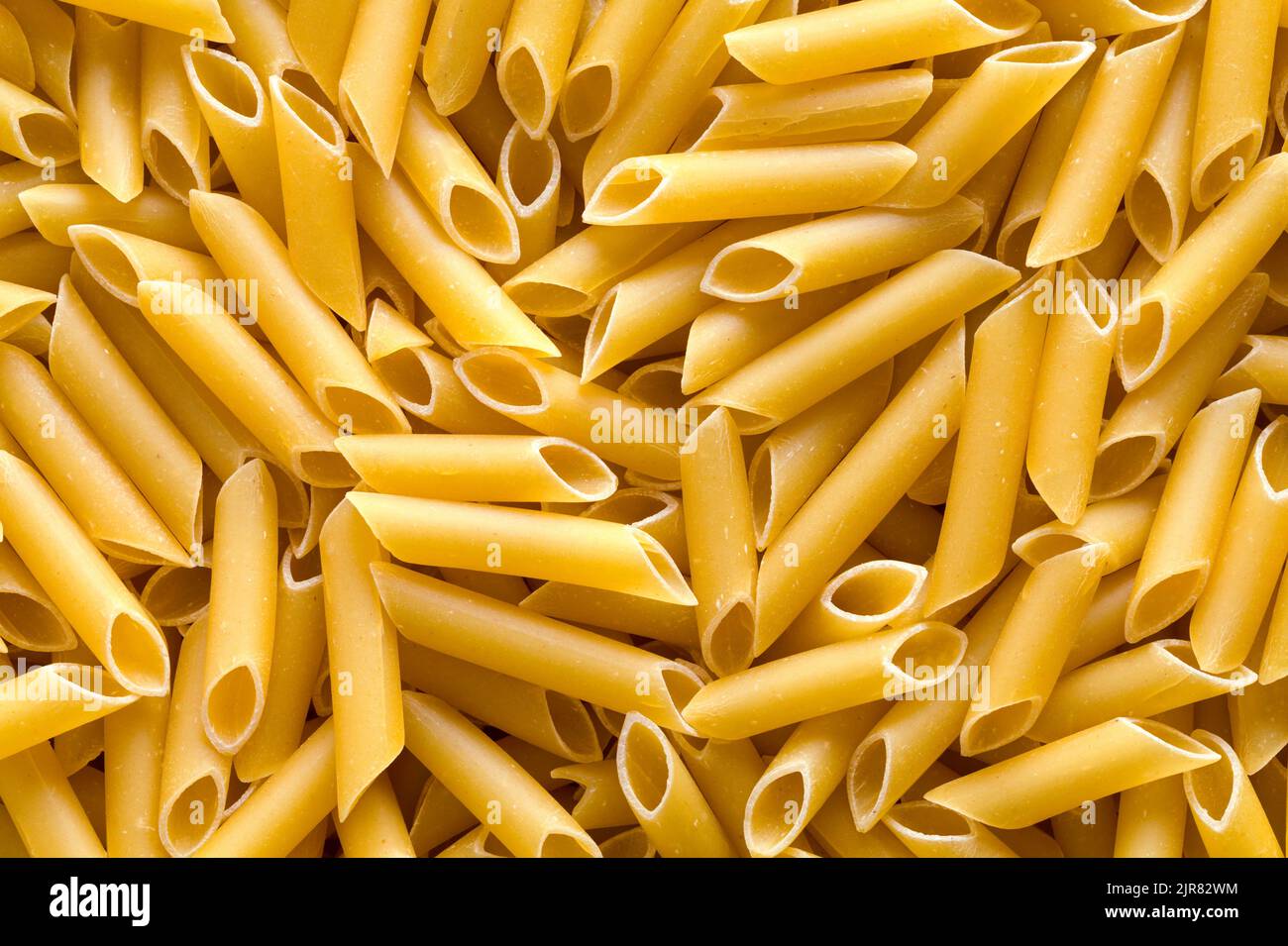 Pile of Penne Pasta Noodles Background Close Up. Stock Photo