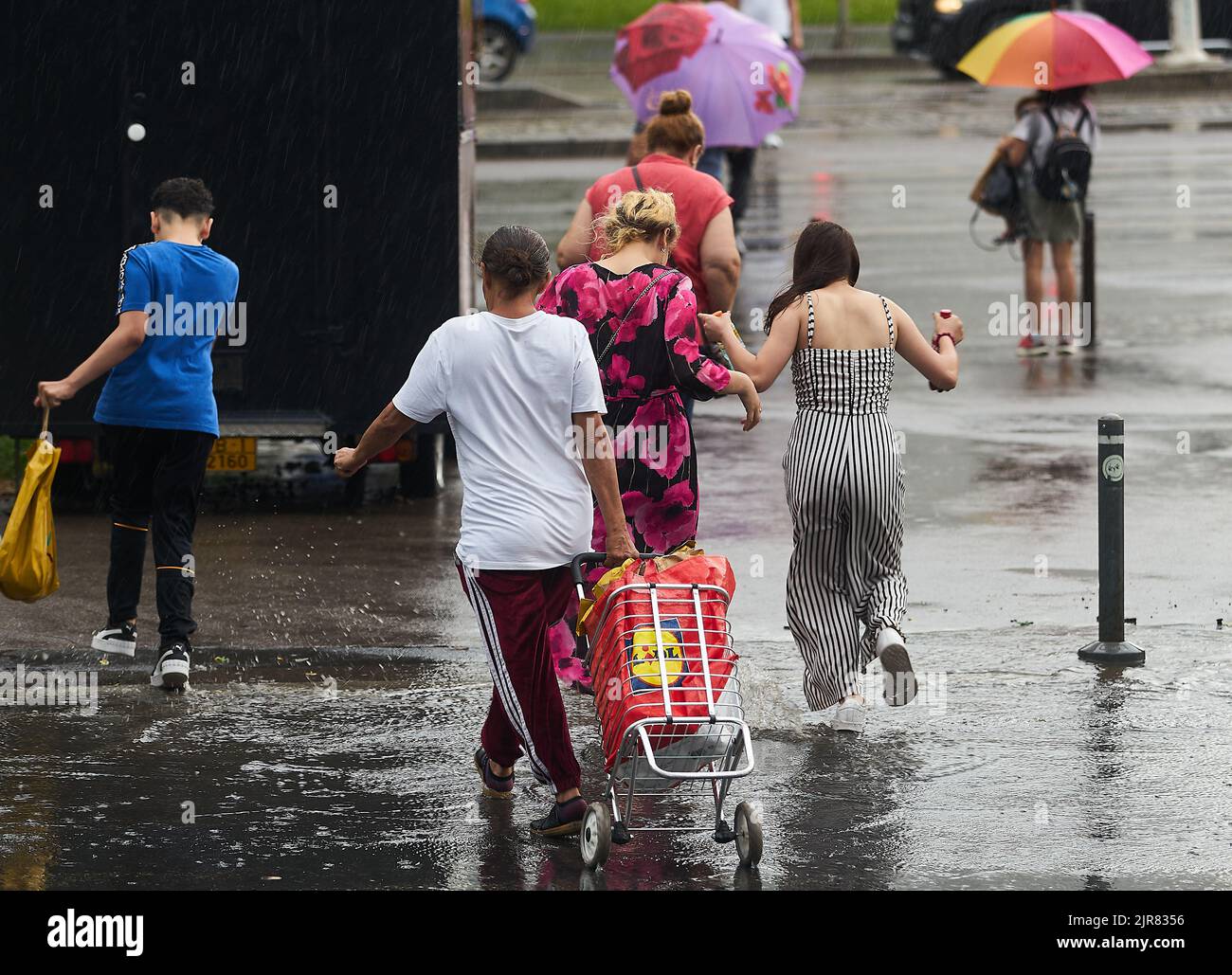 Bucharest, Romania - June 17, 2022: People cross the street during heavy rain. Stock Photo