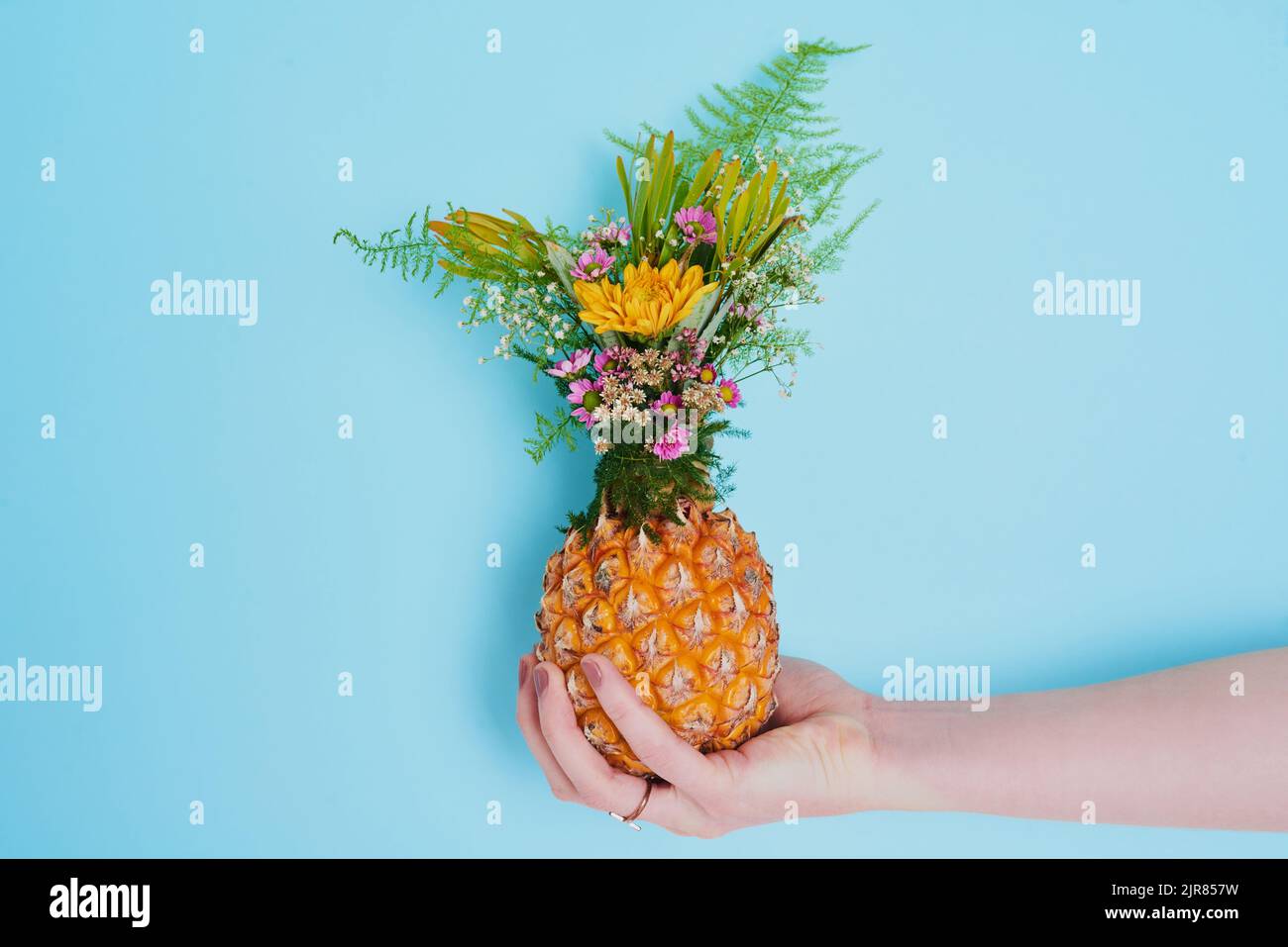 Who says flowers only belong in vases. an unrecognizable woman holding a pineapple stuffed with flowers. Stock Photo