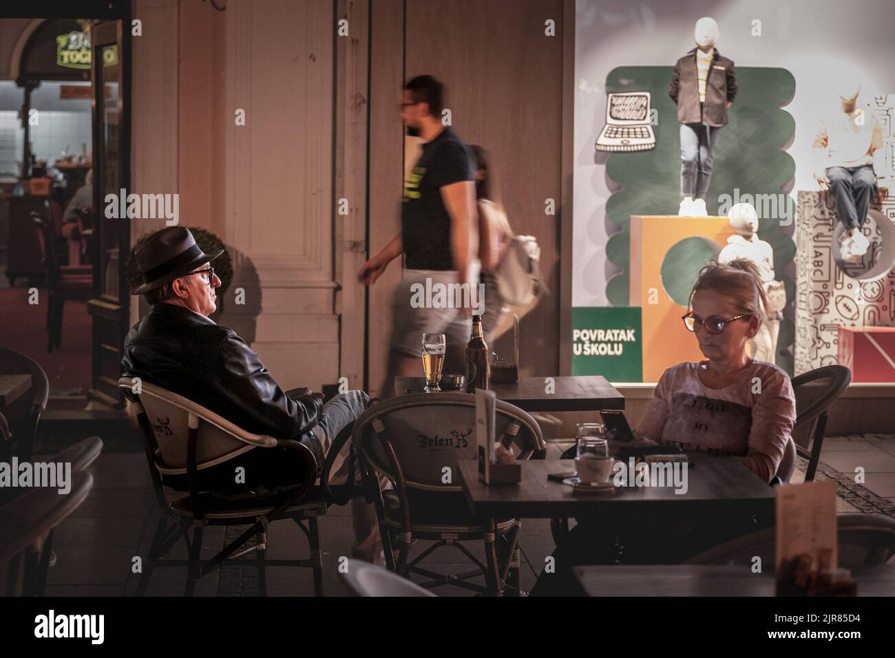 Picture of an old man sitting at the terrace of a bar, at night ...