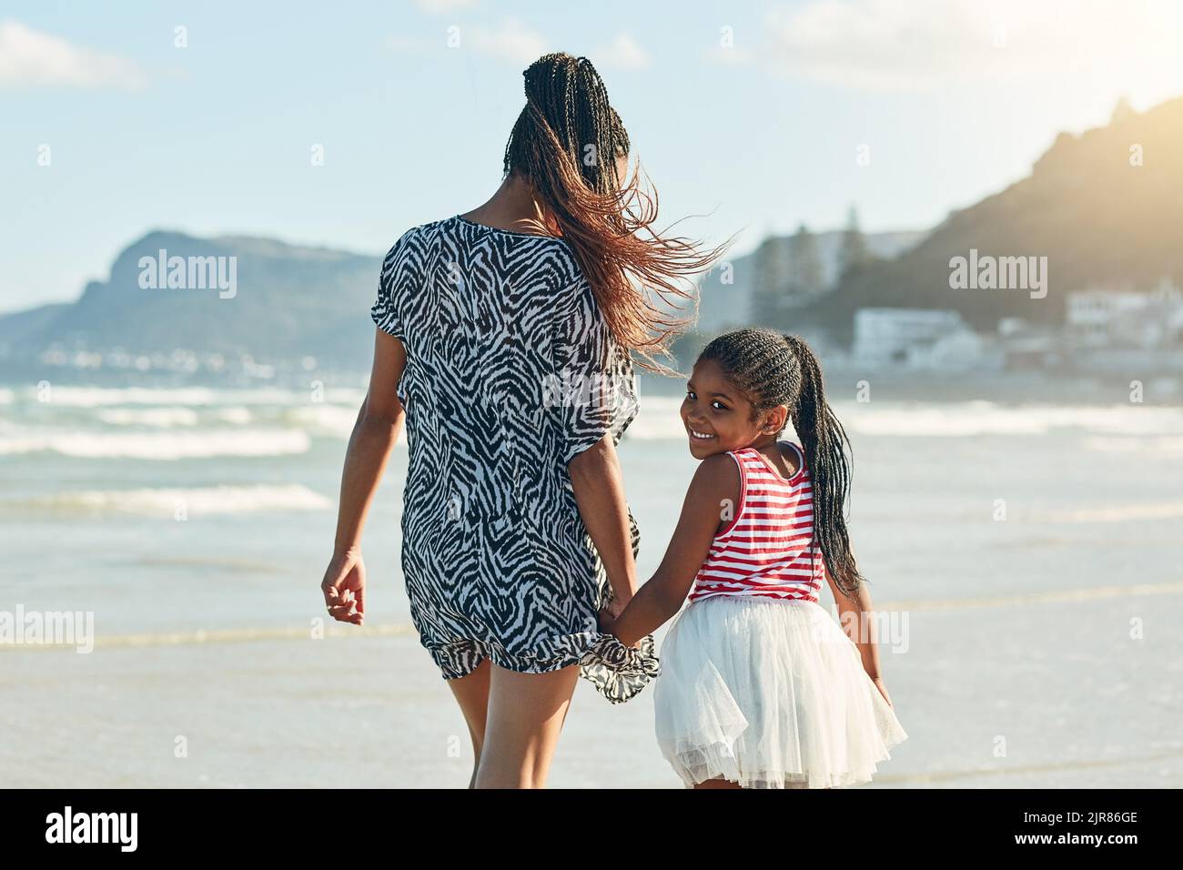 Shell follow in her moms footsteps. Portrait of a little girl enjoying a walk along the beach with her mother. Stock Photo