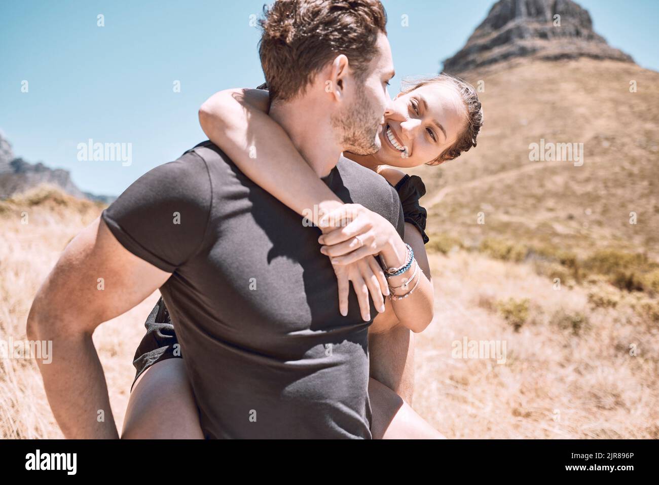 Piggyback, happy and in love couple having fun, being active and enjoying quality time together outdoors. Cute, sweet and loving boyfriend and Stock Photo