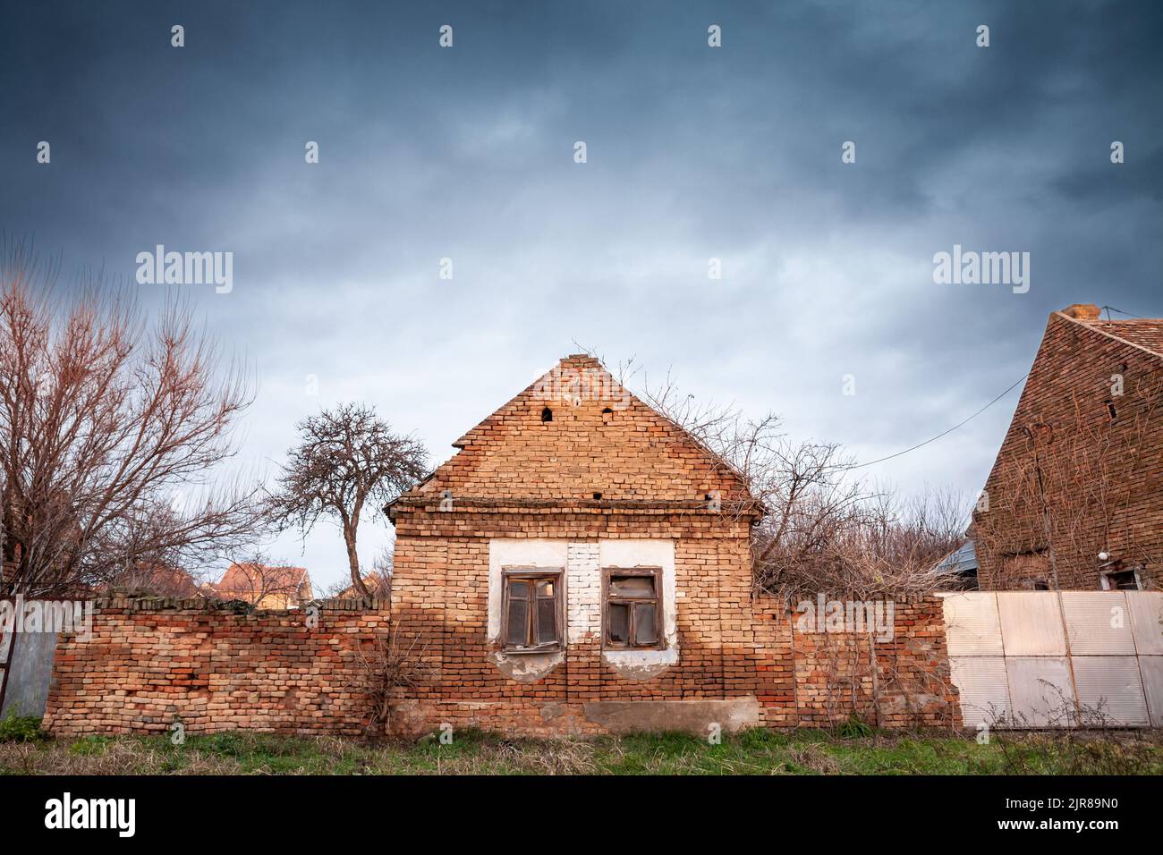 Picture of an abandoned farm in Vojvodina, in Serbia, with the facade of its main house being heavily damaged and decaying. Stock Photo