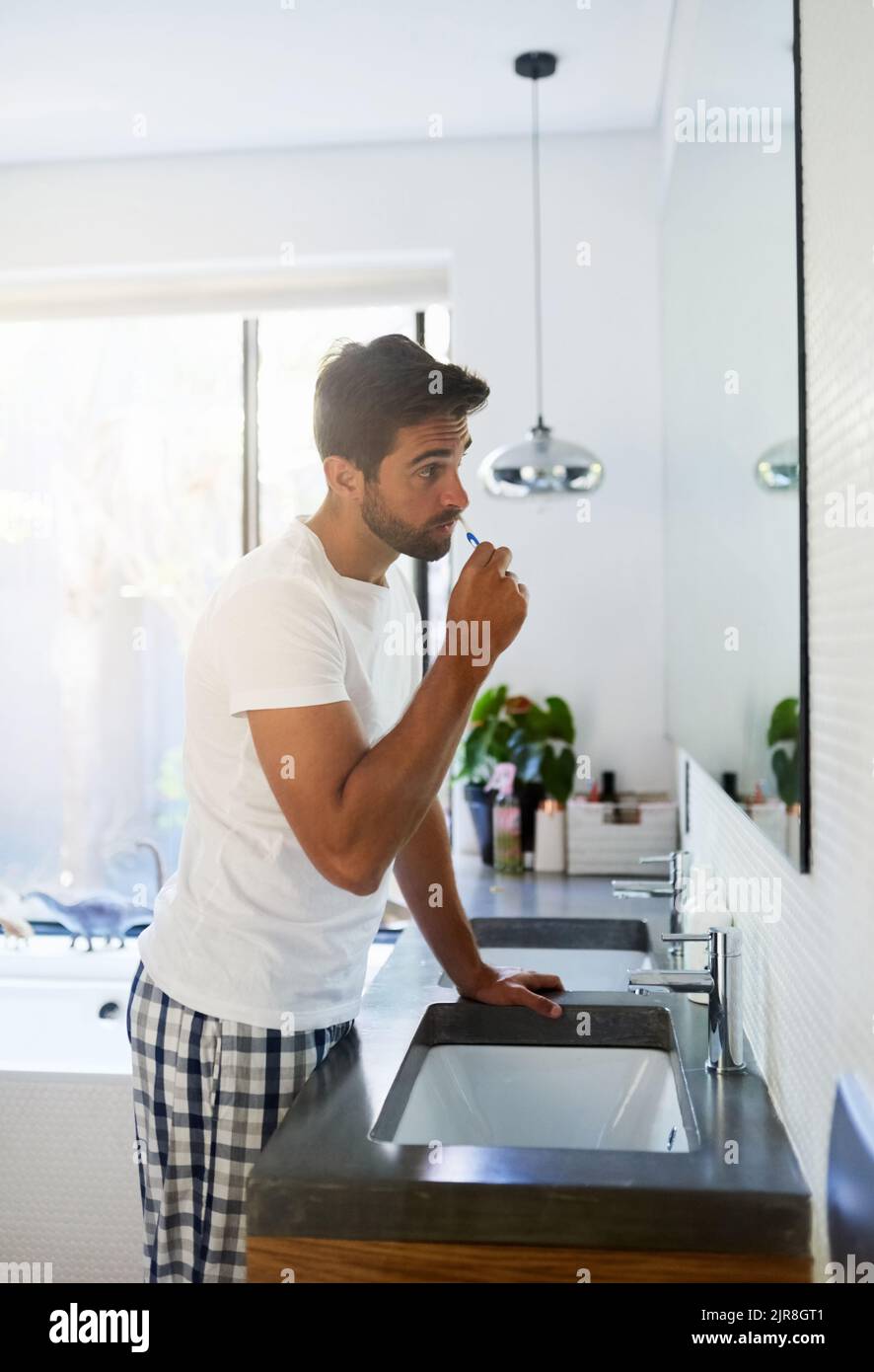 Clean the entire mouth correctly to avoid the dentist. a handsome man brushing his teeth in the bathroom at home. Stock Photo
