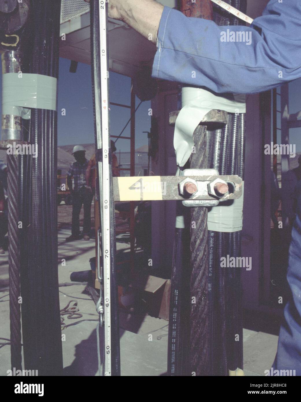 A771176 U7AE STRAKE DOWNHOLE OPERATION JOHN BROUILLARD (PROJECT ENGINEER) JUL 14 77 EG&G/NTS PHOTO LAB Publication Date: 7/14/1977  BROUILLARD, JOHN; CABLES, COAXIAL; CONSTRUCTION HATS; DOWNHOLE OPERATION; EDGERTON, GERMESHAUSEN & GRIER; EG&G; EQUIPMENT & INSTRUMENTS; INSTRUMENTS & EQUIPMENT; MEASURED; MEASUREMENT & RELATIONSHIP; MEASURING DEVICES (EXC UTENSIL; NEVADA; NEVADA TEST SITE; NTS; NUCLEAR ENERGY TECHNOLOGY; NUCLEAR TESTING; NUCLEAR TESTS; STRAKE; TAPE MEASURES; TEST SITES; UGT; UNDERGROUND TESTING  historical images. 1972 - 2012. Department of Energy. National Nuclear Security Admin Stock Photo