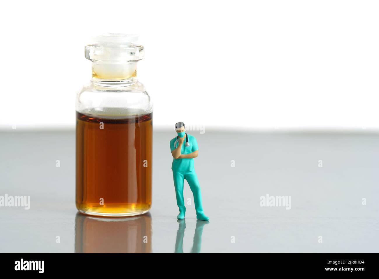 Miniature people toy figure photography. Urine test concept. A nurse standing in front of ampoule bottle with brown orange urine. Image photo Stock Photo