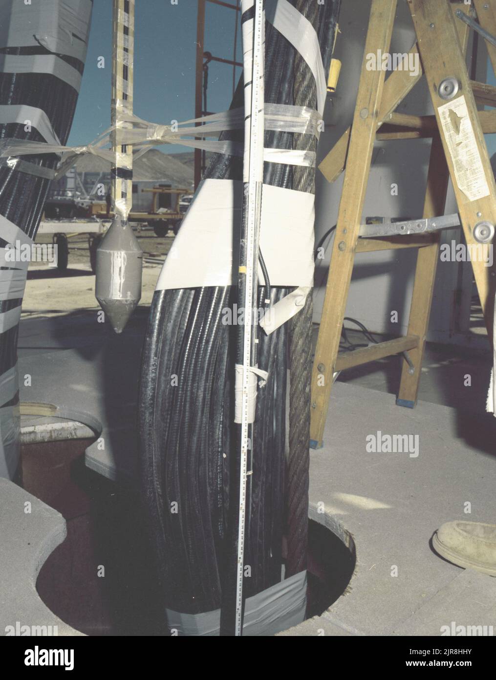 A771168 U7AE STRAKE DOWNHOLE OPERATION JOHN BROUILLARD (PROJECT ENGINEER) JUL 14 77 EG&G/NTS PHOTO LAB Publication Date: 7/14/1977  BROUILLARD, JOHN; CABLES, COAXIAL; DOWNHOLE OPERATION; EDGERTON, GERMESHAUSEN & GRIER; EG&G; EQUIPMENT & INSTRUMENTS; INSTRUMENTS & EQUIPMENT; LADDERS; MEASURED; MEASUREMENT & RELATIONSHIP; MEASURING DEVICES (EXC UTENSIL; NEVADA; NEVADA TEST SITE; NTS; NUCLEAR ENERGY TECHNOLOGY; NUCLEAR TESTING; NUCLEAR TESTS; STRAKE; TAPE MEASURES; TEST SITES; UGT; UNDERGROUND TESTING  historical images. 1972 - 2012. Department of Energy. National Nuclear Security Administration. Stock Photo