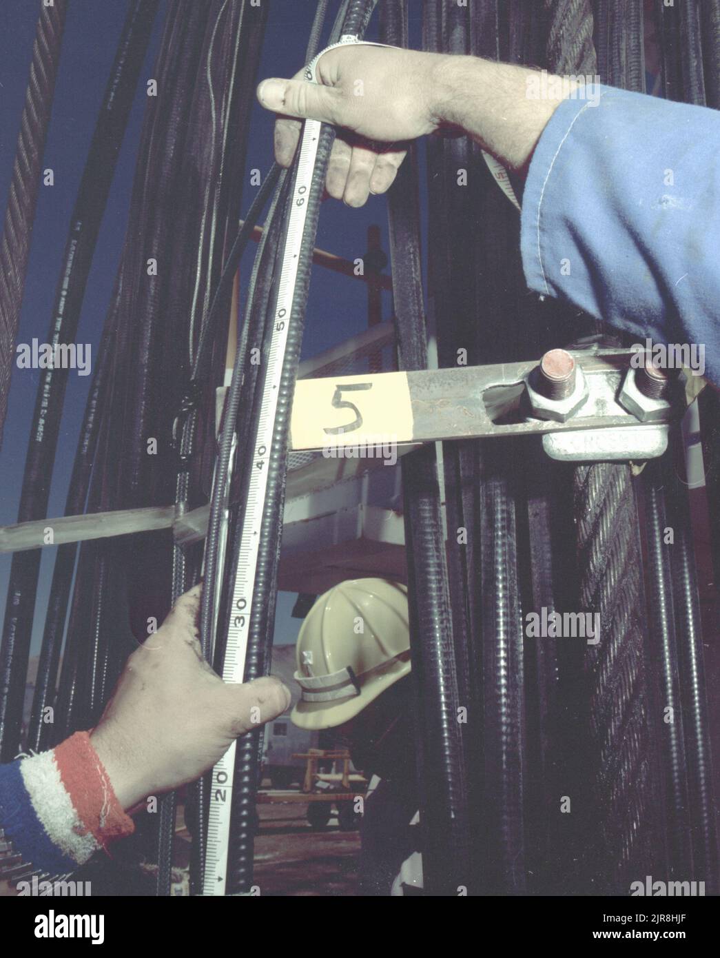 A771175 U7AE STRAKE DOWNHOLE OPERATION JOHN BROUILLARD (PROJECT ENGINEER) JUL 14 77 EG&G/NTS PHOTO LAB Publication Date: 7/14/1977  BROUILLARD, JOHN; CABLES, COAXIAL; CONSTRUCTION HATS; DOWNHOLE OPERATION; EDGERTON, GERMESHAUSEN & GRIER; EG&G; EQUIPMENT & INSTRUMENTS; INSTRUMENTS & EQUIPMENT; MEASURED; MEASUREMENT & RELATIONSHIP; MEASURING DEVICES (EXC UTENSIL; NEVADA; NEVADA TEST SITE; NTS; NUCLEAR ENERGY TECHNOLOGY; NUCLEAR TESTING; NUCLEAR TESTS; STRAKE; TAPE MEASURES; TEST SITES; UGT; UNDERGROUND TESTING  historical images. 1972 - 2012. Department of Energy. National Nuclear Security Admin Stock Photo