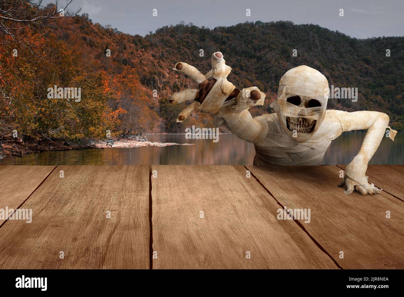 Mummy with skull head crawling with a lake and hill background. Halloween concept Stock Photo