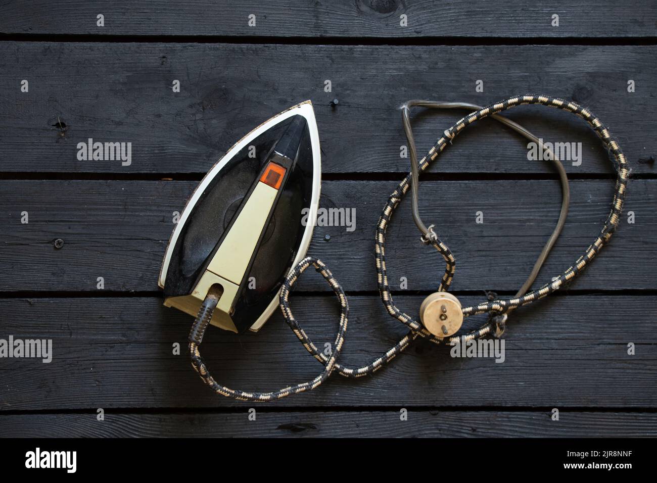 an old electric iron stands on a black wooden floor, a soviet iron Stock Photo