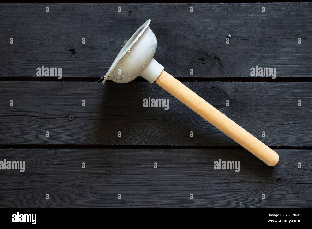 new rubber plunger on black wooden surface, plumber repair, toilet bowl cleaning Stock Photo