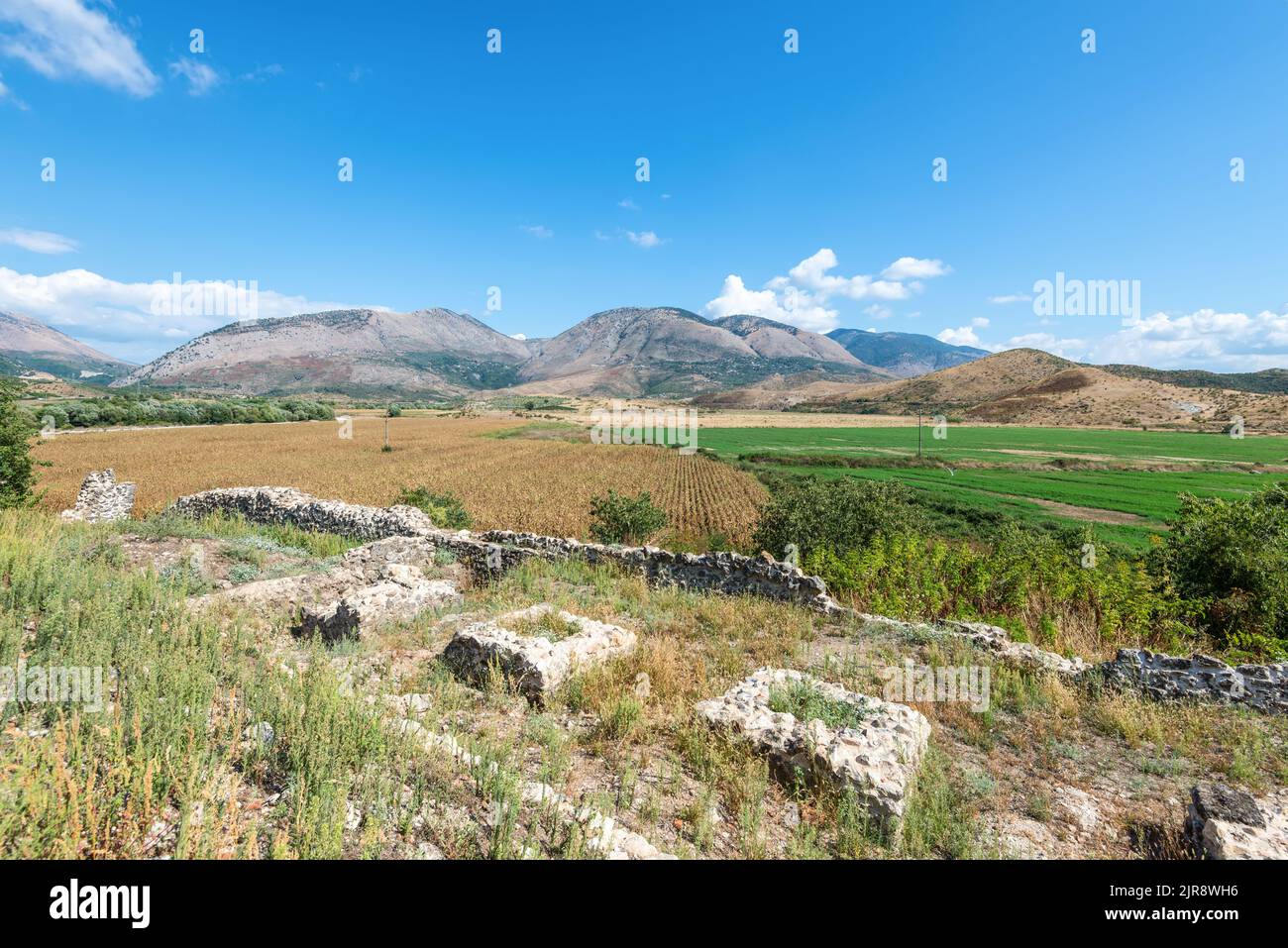 Idyllic landscape with agricultural fields surrounded by mountains in southern Albania near the abandoned Orthodox monastery Stock Photo