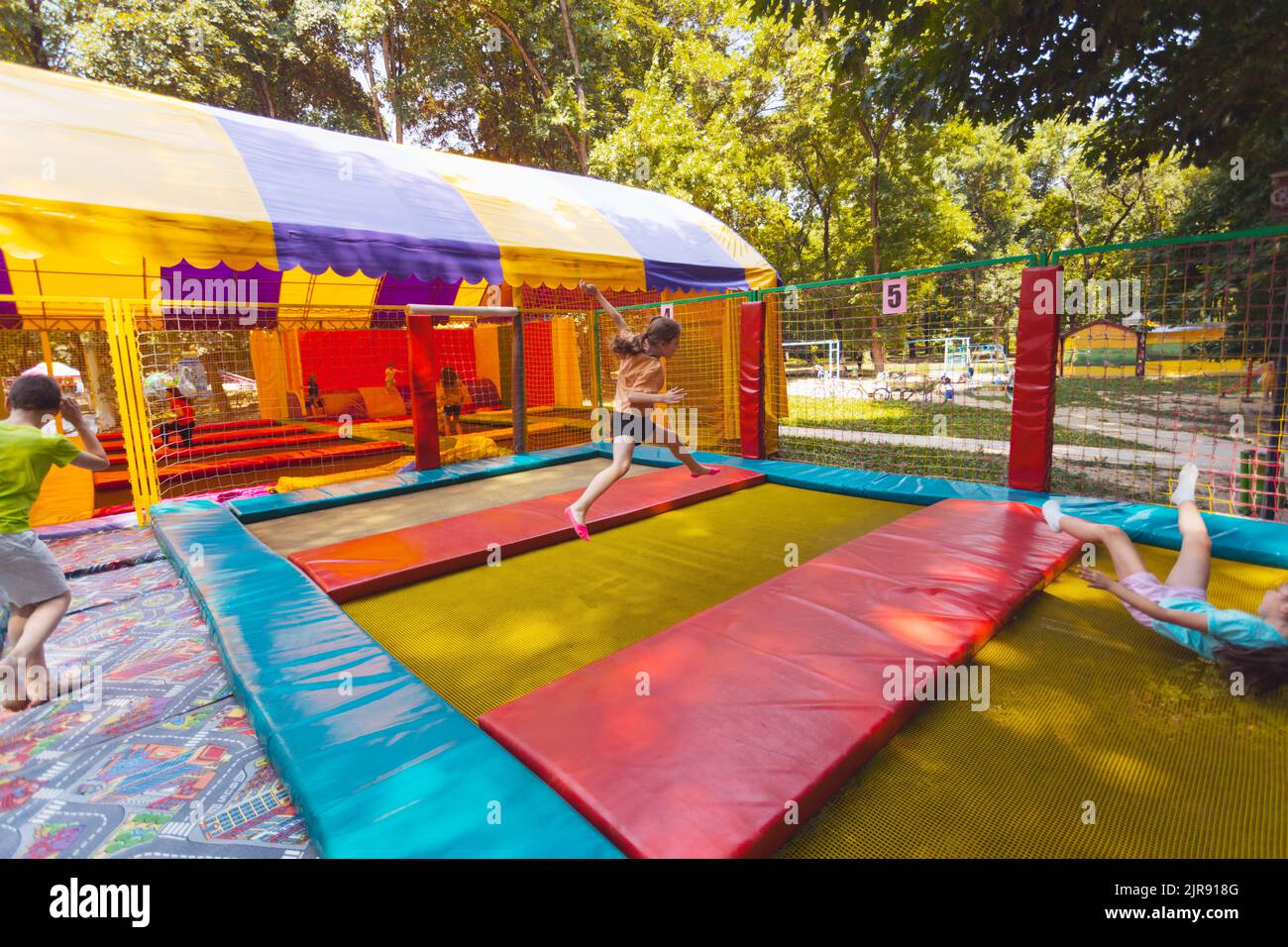 The young children are jumping in the bright trampoline park outdoors in the summer park Stock Photo