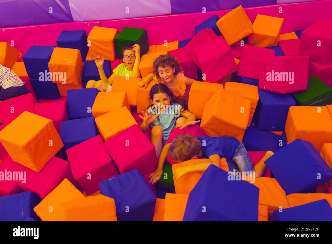 The children are playing with soft cubes in the dry pool. The children of all ages rest in the trampoline park Stock Photo