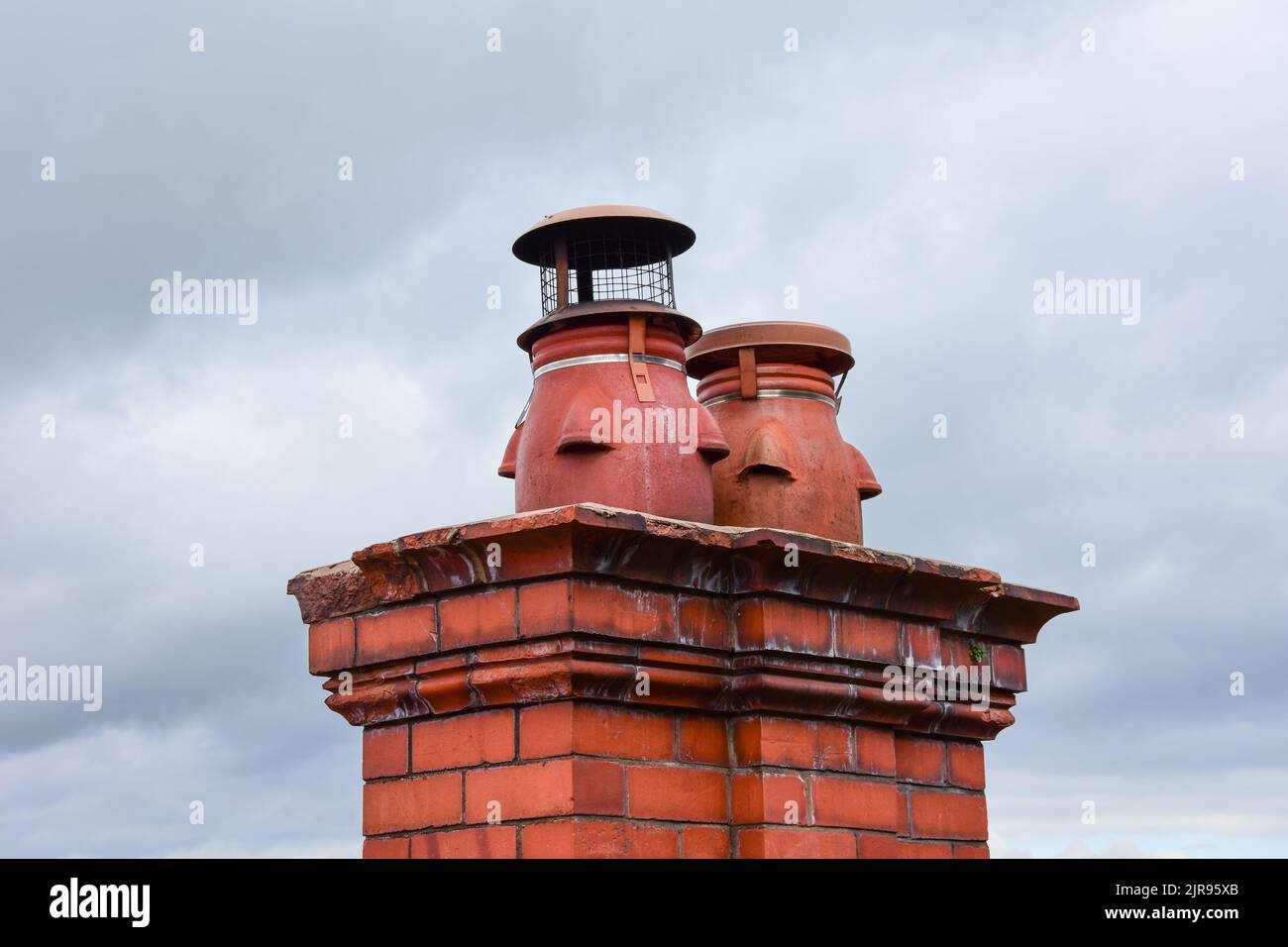 Clay chimney pots on the top of red brick chimney stack of a residential house Stock Photo