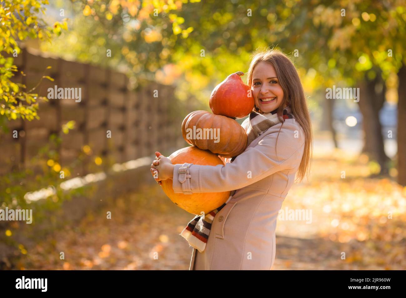 Portrait of happy smile woman with pumpkins in hand. Cozy autumn vibes Halloween, Thanksgiving day. Stock Photo
